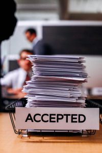 Photo of a pile of papers and a label that says "Accepted"