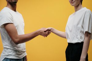 Two people shaking hands against a plain yellow background